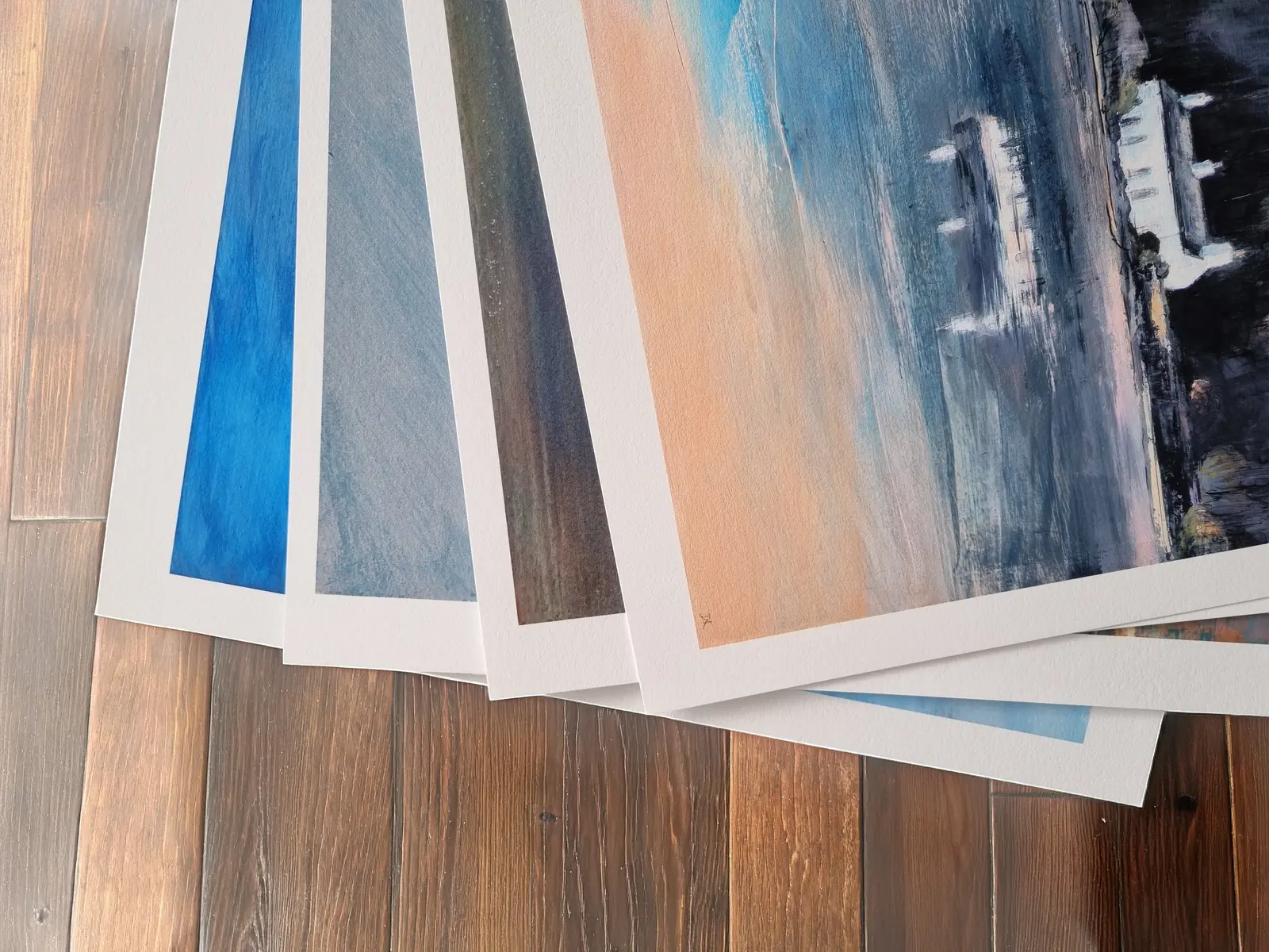 A fan of finished giclée prints spread across the studio floor